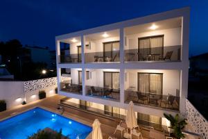 カリテア・ハルキディキにあるElegant Maltepe by Travel Pro Services - Kallithea Halkidikiの夜間のスイミングプール付きのアパートメントビル