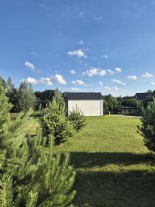 a house in a field with trees in the foreground at Chill in Lubrza in Lubrza