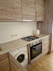 a kitchen with a stove and a washing machine at Apartamentai AKVIJOLA in Vilkaviškis