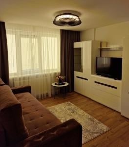 a living room with a couch and a television at Apartamentai AKVIJOLA in Vilkaviškis +8 photos