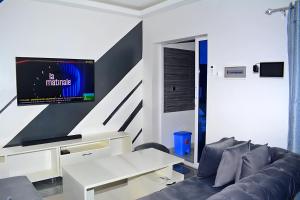 een woonkamer met een bank en een tv aan de muur bij Appart city in Tokpokondji