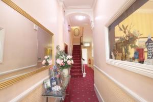 un pasillo con un jarrón de flores en una habitación en Balmoral House Hotel, en Londres