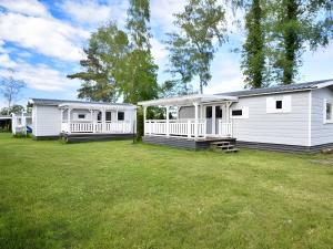 eine Reihe weißer Mobilheime in einem Hof in der Unterkunft Delta Mare - Ferienhaus Folklore - 250m zum Strand in Dziwnów