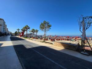a street with a beach with palm trees and chairs at Prestige Beach Apartment in Durrës