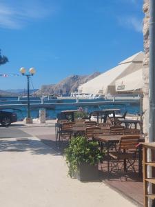 a group of wooden tables and chairs next to the water at Studio Nikola in Baška