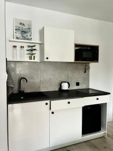a white kitchen with a sink and a microwave at Madi Apartamenty in Sandomierz