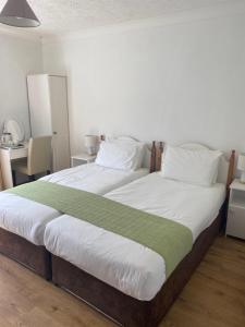 a large bed with white sheets and green blanket at Doonhill Lodge in Galway