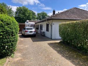a car parked next to a house with a trailer at Gemütlicher Bungalow in Barum