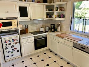 a kitchen with white cabinets and a refrigerator at Gemütlicher Bungalow in Barum