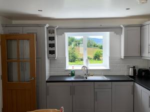 eine Küche mit Spüle und Fenster in der Unterkunft Mourne Country Cottage in Warrenpoint