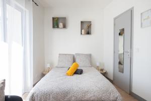 a bedroom with a bed with a yellow pillow on it at Le Partage des eaux - 4 couchages - Hypercentre - Clim - Wifi in LʼIsle-sur-la-Sorgue