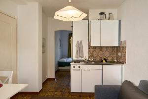Una cocina con gabinetes blancos y un fregadero. en Tiny Locarno Area Apartment, en Losone