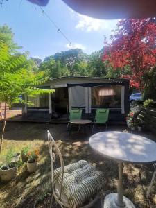 a patio with a table and chairs and a tent at CampOloHel- przyczepa kempingowa in Hel