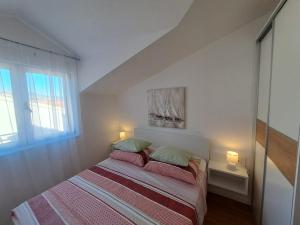 ein Schlafzimmer mit einem Bett mit zwei Kissen und einem Fenster in der Unterkunft Apartmani Peran in Grebaštica