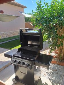 a bbq grill on a stand in a yard at Kuća za odmor L&L in Bibinje