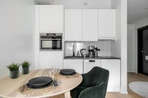 a kitchen with white cabinets and a table and chairs at Brand new apartment - Minerva in Turku