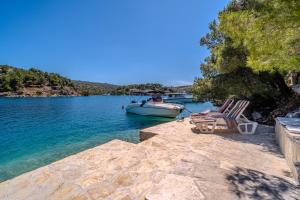 ein Boot liegt mit zwei Stühlen an einem See in der Unterkunft Villa Dupin Oceanfront with boat dock in Bobovišća