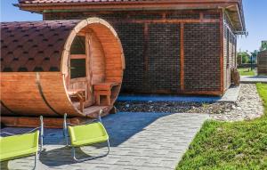 a wooden cabin with two chairs in front of it at Cozy Home In Glowczyce With Sauna in Główczyce