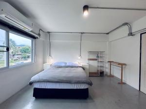 a bedroom with a bed in a room with a window at Prachan Hostel in Thong Sala