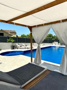a swimming pool with a white umbrella next to a swimming pool at HelaMoni, New 5 Star 2 Person apartments with pool in Malinska