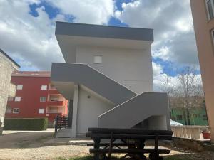 a white building with a staircase next to a bench at Medjugorje Apartments Centre in Međugorje