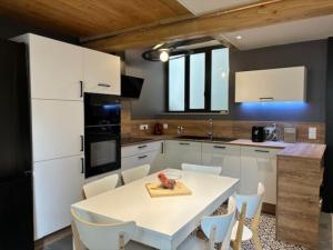 a kitchen with a white table and white cabinets at Le Patio de l'Abbaye in Cluny