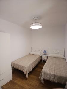 - 2 lits dans une chambre blanche avec une lampe dans l'établissement Casa Gardenia centro historico a 200m de la playa sólo familias, à Conil de la Frontera
