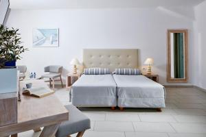 um quarto com uma cama grande, uma mesa e cadeiras em Aegean Plaza Hotel em Kamari