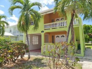 a yellow house with palm trees in front of it at 3 Palms by Coastal View7 in Christ Church