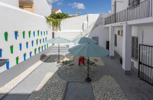 dois guarda-sóis, mesas e cadeiras em um pátio em Apartamentos Casa Rosaleda em Jerez de la Frontera