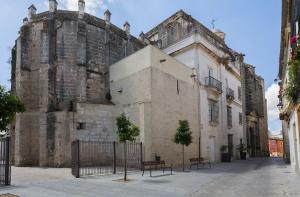 um edifício antigo com bancos à frente em Apartamentos Casa Rosaleda em Jerez de la Frontera