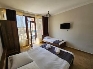 una camera da letto con due letti e una TV a parete di Guest House Gio a Kobuleti