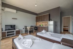 two beds in a room with a kitchen and a tv at Denis Apartments in Sarandë