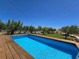 a blue swimming pool with a wooden deck and trees at Trulli Nannì in Locorotondo