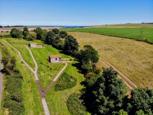 an aerial view of a field with a house and a road at Anniston Mill Cabin 1 in Arbroath