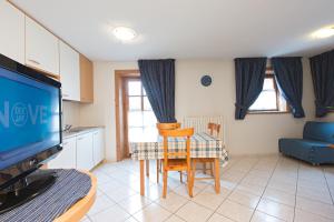 ein Wohnzimmer mit einem Tisch und eine Küche mit einem TV in der Unterkunft Bait Vegl in Livigno