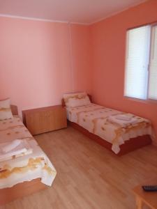 two beds in a room with pink walls and wooden floors at Къща бунгало Градината in Krapets
