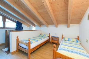 two beds in a room with wooden ceilings at Bait Vegl in Livigno