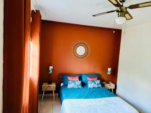 a bedroom with a blue bed with an orange headboard at Appartement Coco Antilles ,vue mer, terrasse couverte 25m2,plage à pied in Sainte-Luce