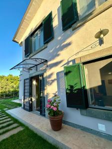a house with green shutters and a potted plant at La Sovrana dei Cimini in Bagnaia