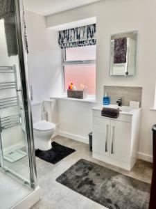 a white bathroom with a toilet and a sink at York House luxury 2 bedroom apartment in Ashby de la Zouch