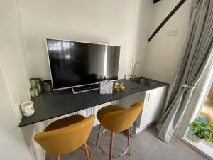 a living room with a television and two chairs at Coachmans Rest in Sandwich