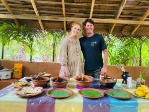 a man and woman standing in front of a table with food at Dew Ashi Homestay in Sigiriya