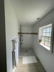 a white bathroom with a shower and a window at James Armistead Lafayette Cottage in Cumberland Landing