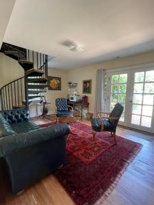 a living room with a couch and a spiral staircase at James Armistead Lafayette Cottage in Cumberland Landing