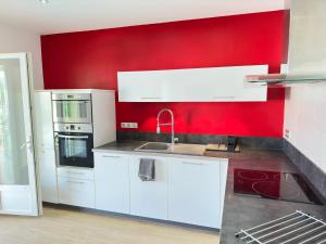 Una cocina con una pared roja y electrodomésticos blancos. en Appartement Logement entier avec piscine, en Biguglia