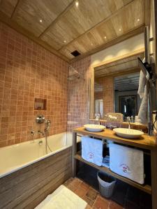 een badkamer met 2 wastafels, een bad en een spiegel bij Hôtel du Château du Rivau in Lémeré