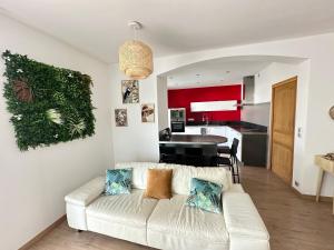 Una sala de estar con un sofá blanco y una cocina. en Appartement Logement entier avec piscine, en Biguglia
