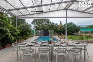mesa de comedor y sillas frente a la piscina en Grey Hues with Swimming Pool & Lawn at Karjat by StayVista, en Karjat