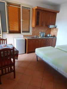a kitchen with wooden cabinets and a table and a bed at Iliria Durres Apartments in Durrës